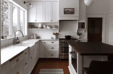 White kitchen with deep wood island and small runner.