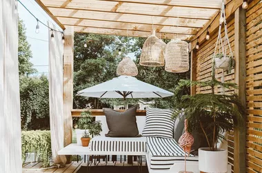 Outdoor wooden pergola with floating sofa underneath.