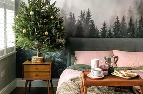 Cute bedroom with small Christmas tree on nightstand. 